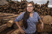 Woman standing with logs at timber mill