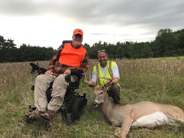 hunter in a wheelchair with a deer he harvested and DNR area wildlife manager next to him