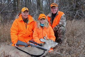 two adults and a youth in blaze orange with deer harvested