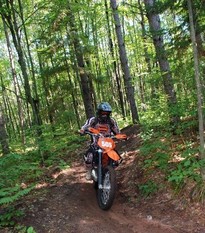 Off-highway motorcycle on trail through the woods