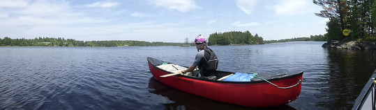 Panoramic photo of the St. Louis River with red canoe and single paddler in foreground