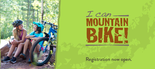 Photo of two young cyclists looking at each other smiling, sitting by bikes, with green graphic and "I Can Mountain Bike" logo.