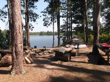 Campsite with lake in background and large trees in foreground