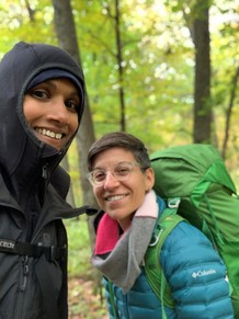 Two women in the woods smiling at the camera