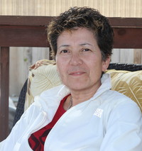Headshot of woman in white shirt, sitting and looking at camera.