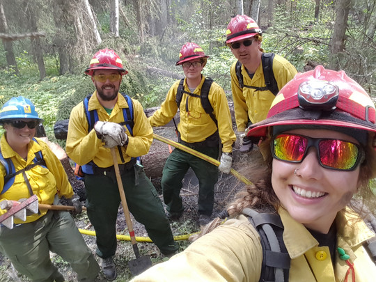 Selfie of a group of five firefighters in yellow jackets and red helmets
