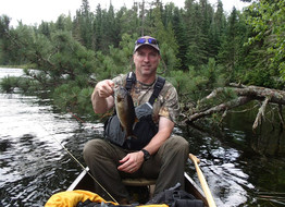 angler in canoe in BWCA holding a smallmouth bass