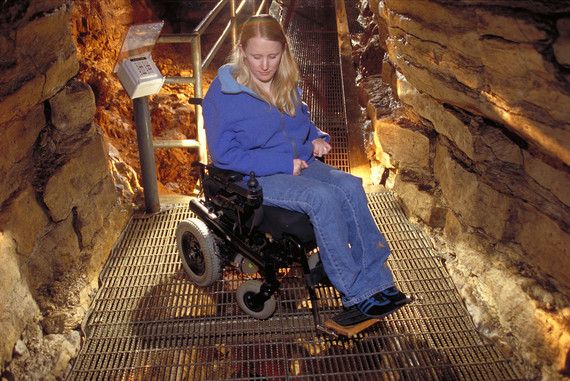 Woman on wheelchair looking down at ramp in cave