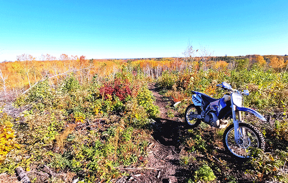 Open field with dirt trail and off highway motorcycle