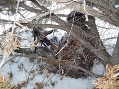 hunter sitting in cover with a rifle during a deer hunt in snow