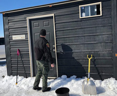 Conservation Officer knocking on the door of an ice house on a lake