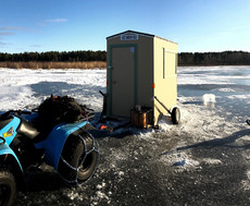 An ice shelter and ATV on ice without much snow cover