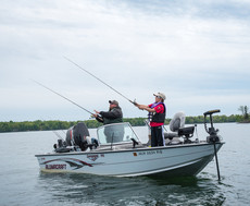 two anglers casting on a lake from a fishing boat