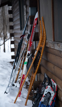 Skis and snowshoes leaning against camper cabin.