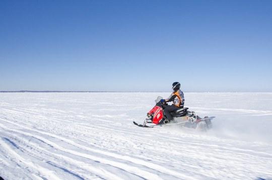 Red snowmobile traveling on frozen lake