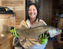 angler in an ice shelter holding a large walleye she caught