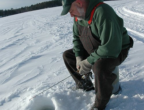 angler sitting on a bucket on a lake fishing