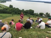A group of prairie practitioners sit on a remnant prairie learning prairie plants
