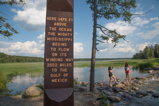 Iconic Mississipi Headwaters monument with people crossing in the summer.