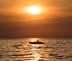 fishing boat on Mille Lacs Lake to backdrop of a red/orange sky