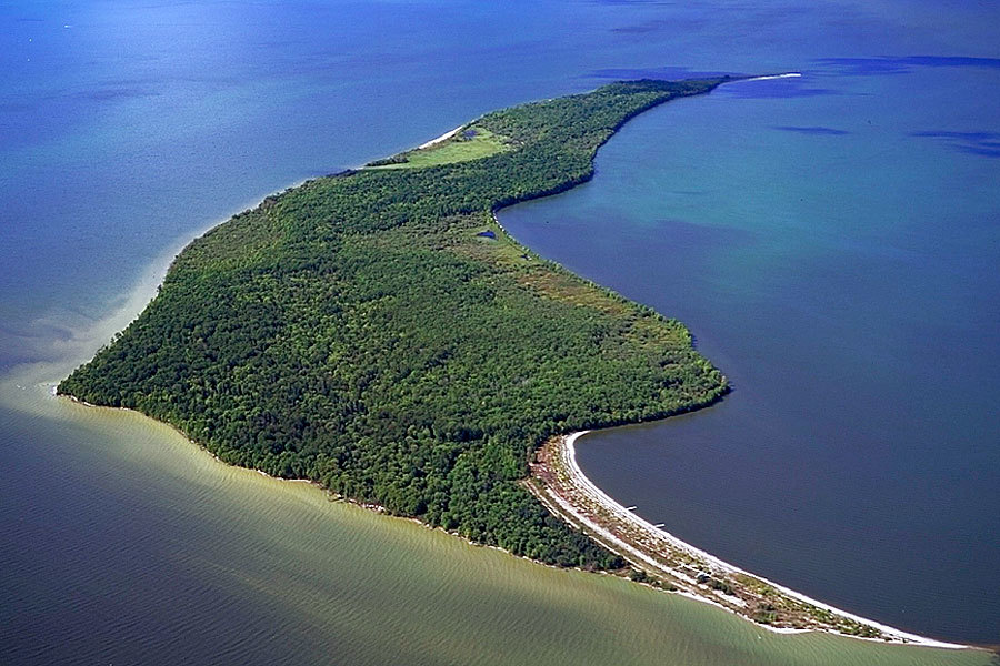 Aerial photo of a wooded island with sandy shores on big lake.