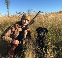 hunter with her gun and dog in habitat