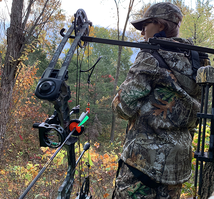 young archery hunter looking off into the distance with bow on a holder