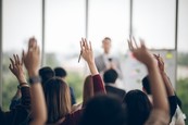 People raising their hands at a seminar