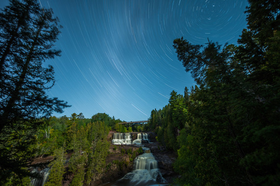 Star trails over waterfalls framed by trees