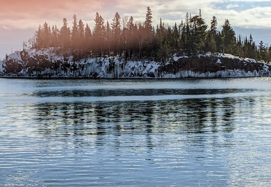 A wintry scene, with snowy trees on an island in a lake