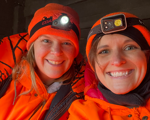 two hunters in blaze orange smiling and with headlamps 