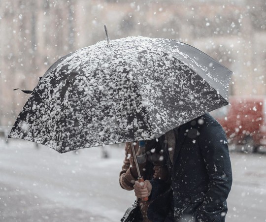 A person holding an umbrella in the snow