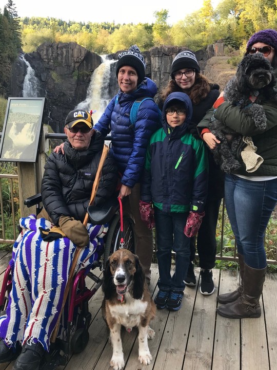 Man on wheelchair and his family, including a dog. at the overlook for the high falls at Grand Portage State Park.