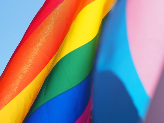 A rainbow flag on the left and a transgender flag on the right