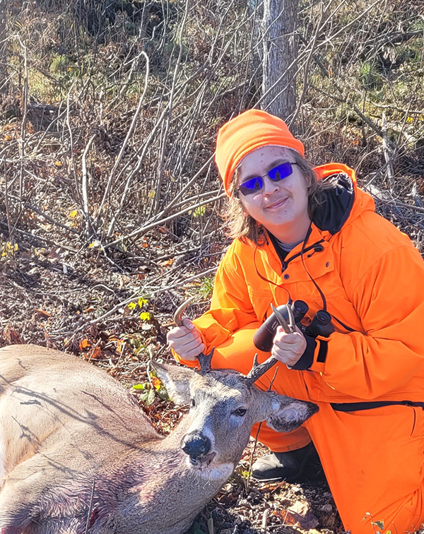 youth hunter in blaze orange with a deer harvested