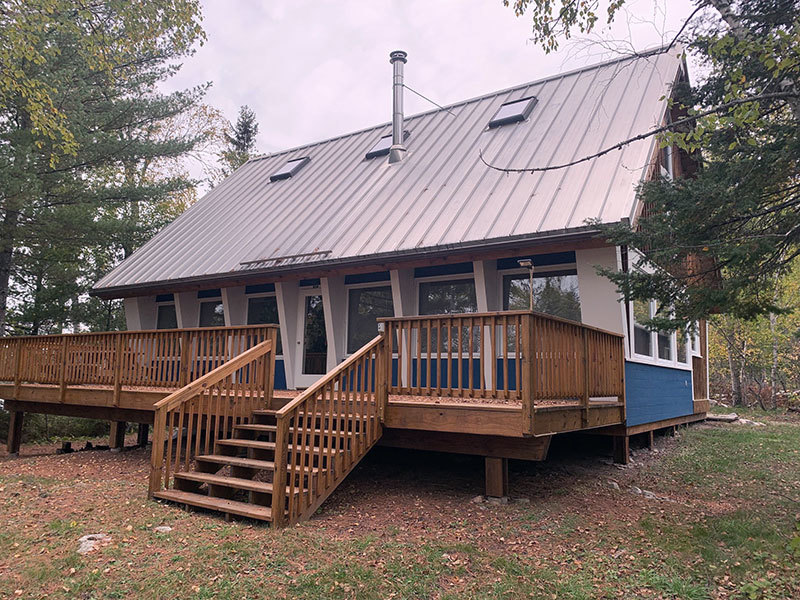 Cabin with metal roof and a deck.