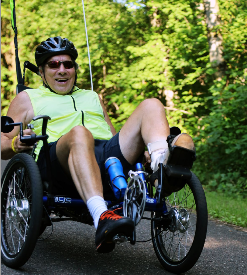 Man on adaptive bike enjoying a ride on an accessible multi-use trail.
