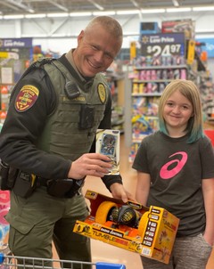 Bret Grundmeier holds a toy and stands next to a kid