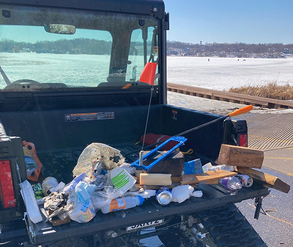 trash on the back of an ATV with tracks on it for driving on ice