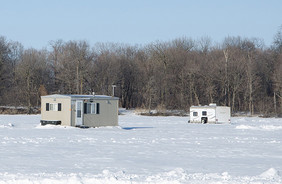 a couple ice houses on a frozen lake