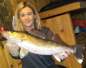 angler and walleye she caught in an ice house