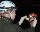 Two people wearing headlamps, with one person holding a bat