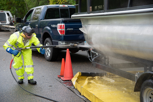 An AIS inspector washes down the side of a boat