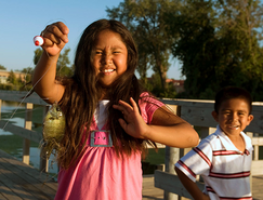 girl and boy on a fishing pier and girl has a sunfish and a bunch of tangled line, smiling 