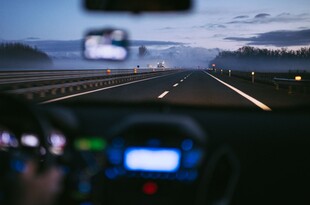 The dashboard of a car, with a road visible through the windshield