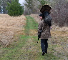 hunter walking away holding a harvested turkey over shoulder