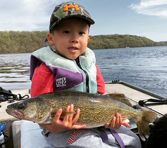 young angler holding a large walleye on a boat