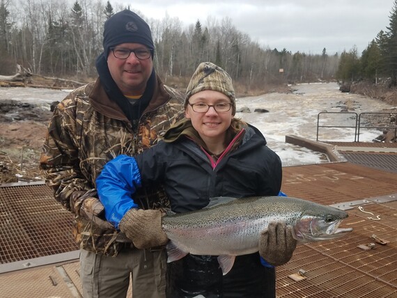 Photo of a father and daughter holding a large steelhead