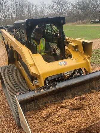 DNR employee operating Skid Steer lifting dirt