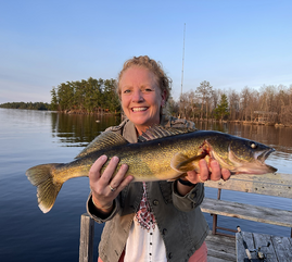 a mom with a nice walleye, and she's standing on a dock